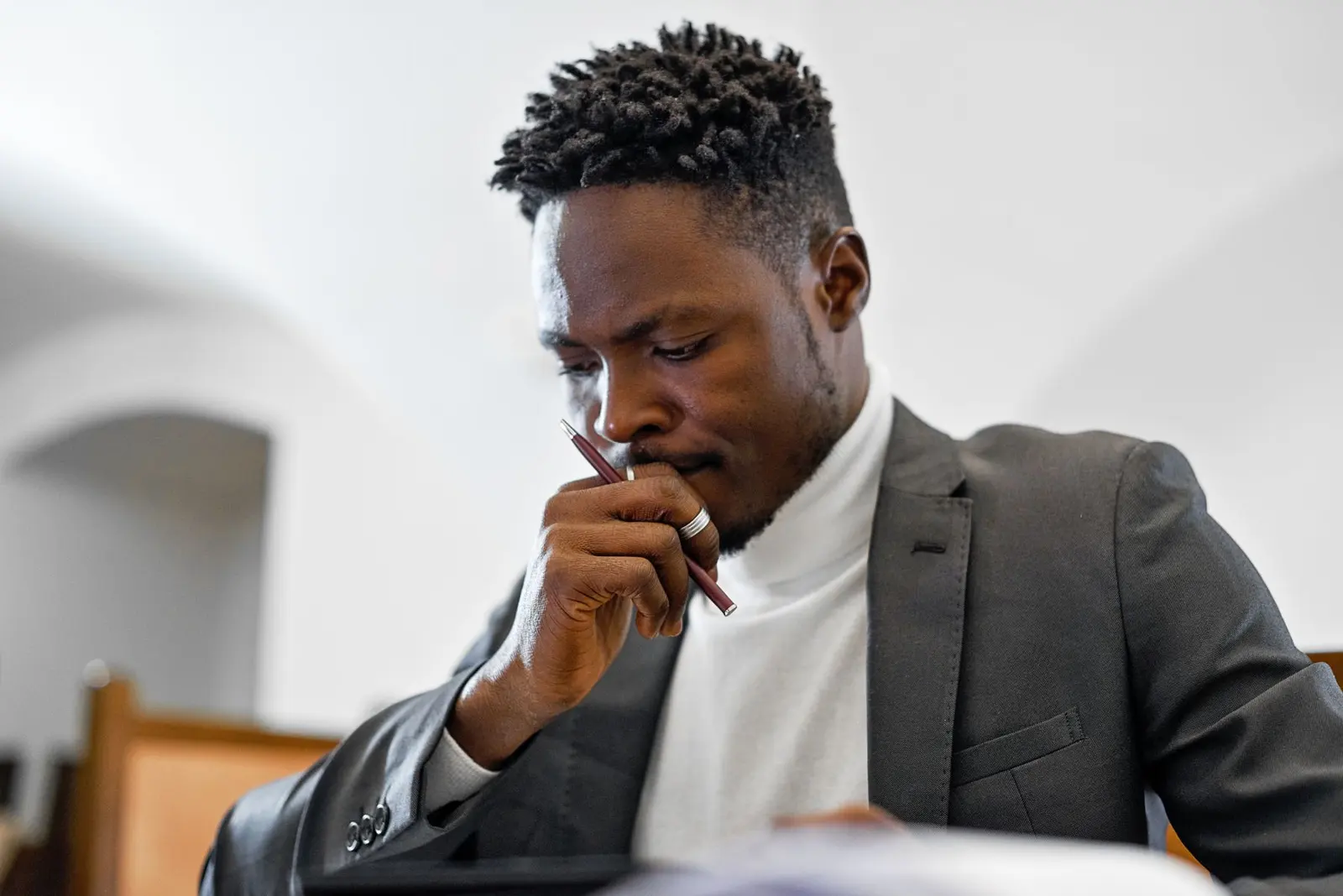 Business owner at his desk, thinking, with a pen in his hand