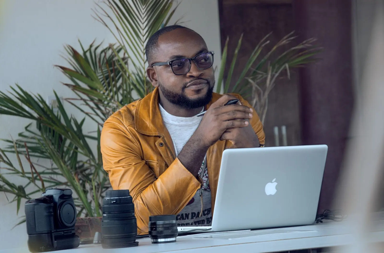 Business owner at a laptop with a camera beside him, preparing photos