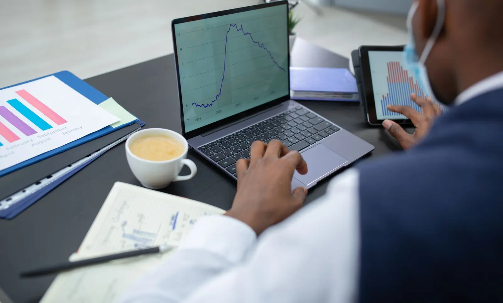 Man reviewing ad performance charts on a laptop and a tablet